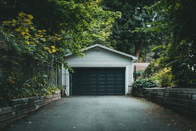 Technician inspecting a garage door with tools.